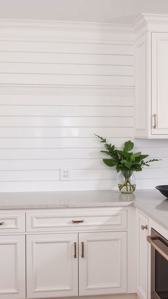 A modern kitchen featuring a white shiplap backsplash with decorative molding, complemented by light cabinetry and a vase of greenery.
